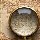 A magnifying glass over a detailed map.